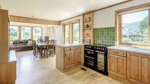 A kitchen with wooden cabinets, a dining area with a sofa, and large windows.