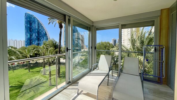 A balcony with a view of a cityscape, including modern buildings and palm trees. - MIRAGOLF PONIENTE DREAM R118 (Benidorm)