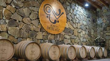 Wooden barrels against a stone wall with a sign reading "BODEGAS ENTREVIZ".