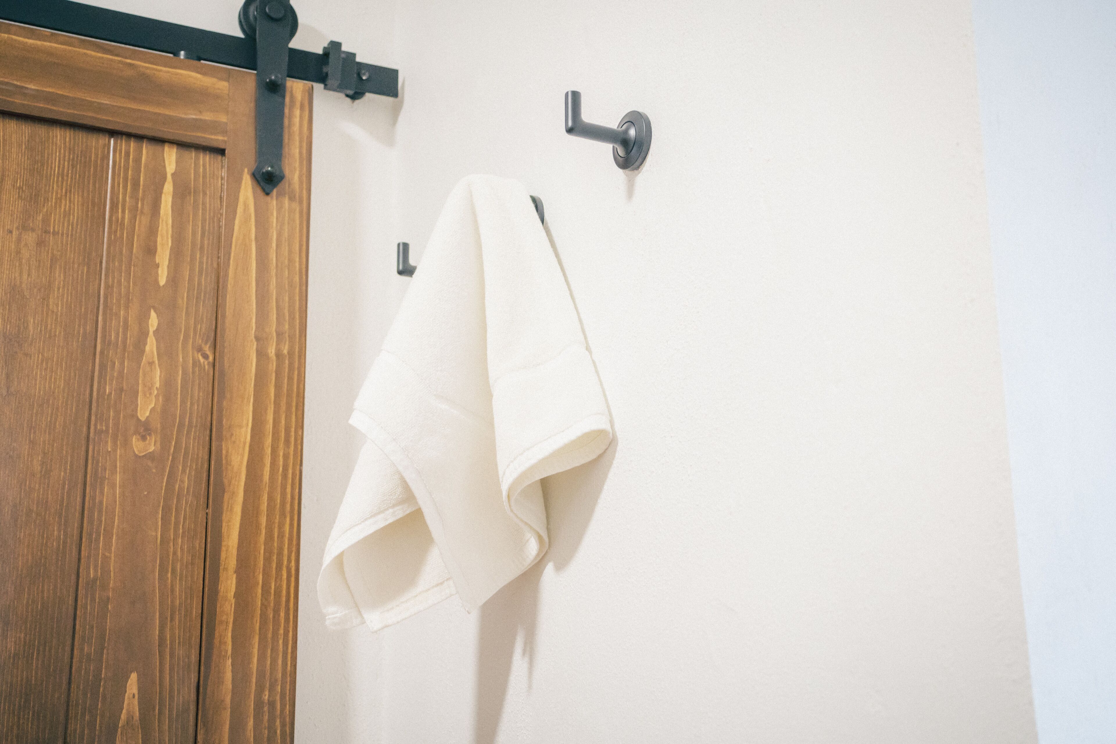 A wooden door with a sliding mechanism and a towel hanging on a hook.