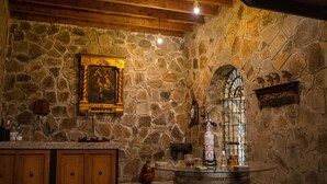 Une pièce aux murs de pierre, avec un plafond en bois, un coin bar et un tableau encadré accroché au mur.