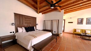 Une chambre avec un plafond en bois, un lit avec une tête de lit en bois, un banc, un fauteuil suspendu et un canapé.