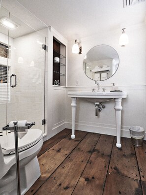 A bathroom with a white toilet, a sink with a mirror, and a shower area. - James Pharmacy Bed & Breakfast (Old Saybrook)