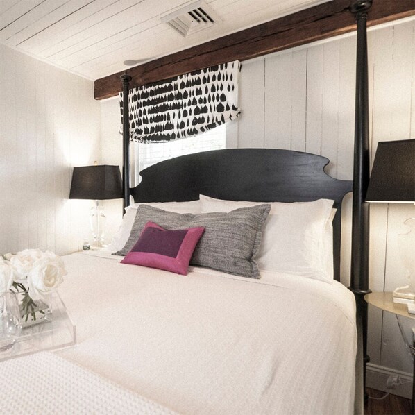 A bedroom with a four-poster bed, white bedding, and a vase of white flowers on the nightstand. - James Pharmacy Bed & Breakfast (Old Saybrook)