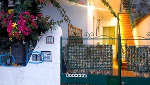 Un edificio de fachada blanca, con el número '62' en la pared, un portón verde con diseño de metal y una escalera que lleva a la entrada.