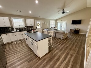 A spacious kitchen with white cabinets, a central island, and a dining area with a sofa and chairs. - Modern barndo, with game room and hot tub (Lancaster)