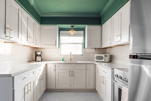 Eine Küche mit weißen Schränken, einem Edelstahl-Kühlschrank, einer Mikrowelle und einer Kaffeemaschine.