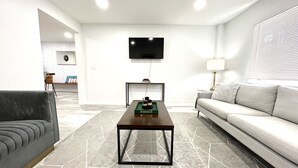 Una sala de estar moderna con un sofá, una mesa de centro y un televisor montado en la pared.