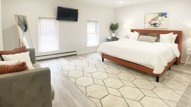 Un dormitorio moderno con una cama grande, un escritorio, una silla y un televisor montado en la pared.
