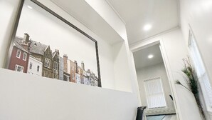 Un interior moderno con una escalera que conduce a una distribución, un cuadro enmarco de edificios y una puerta a otra habitación.