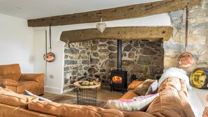 Una sala de estar acogedora con una chimenea de piedra, sofá de cuero y techo rústico.