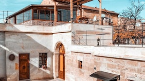 A courtyard with a stone building, a wooden pergola, and outdoor furniture. - Lavinia Cappadocia (Ürgüp)