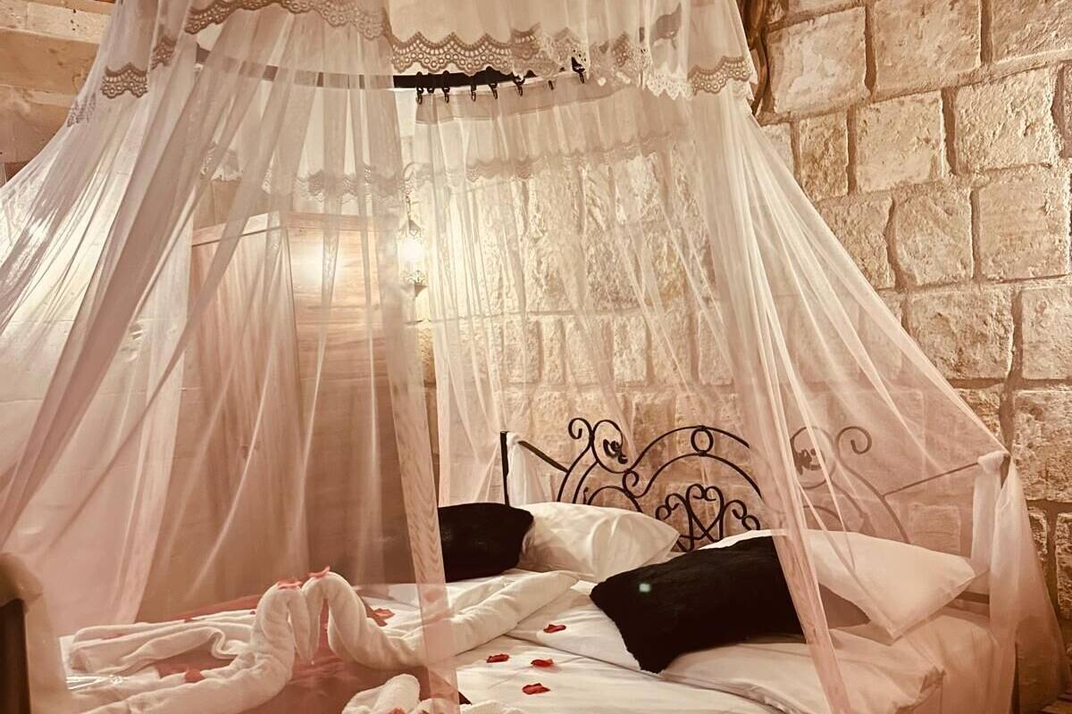 A bed with a canopy, a stone wall, and a wooden ceiling.