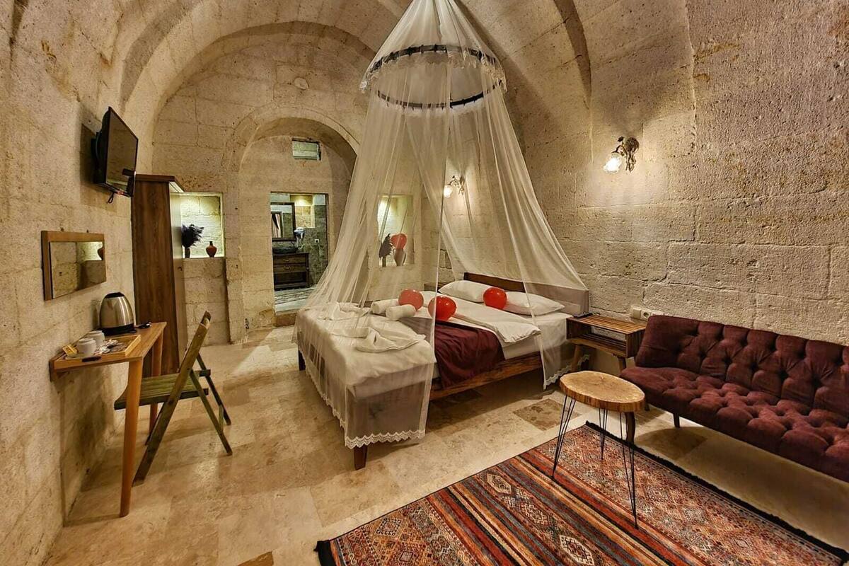 A bedroom with a canopy bed, a sofa, a small table, and a chair.