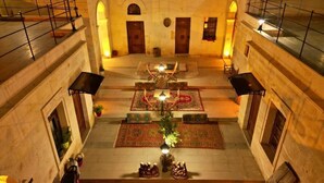 A multi-level atrium with a central courtyard featuring a decorative fountain, potted plants, and patterned rugs. - Lavinia Cappadocia (Ürgüp)