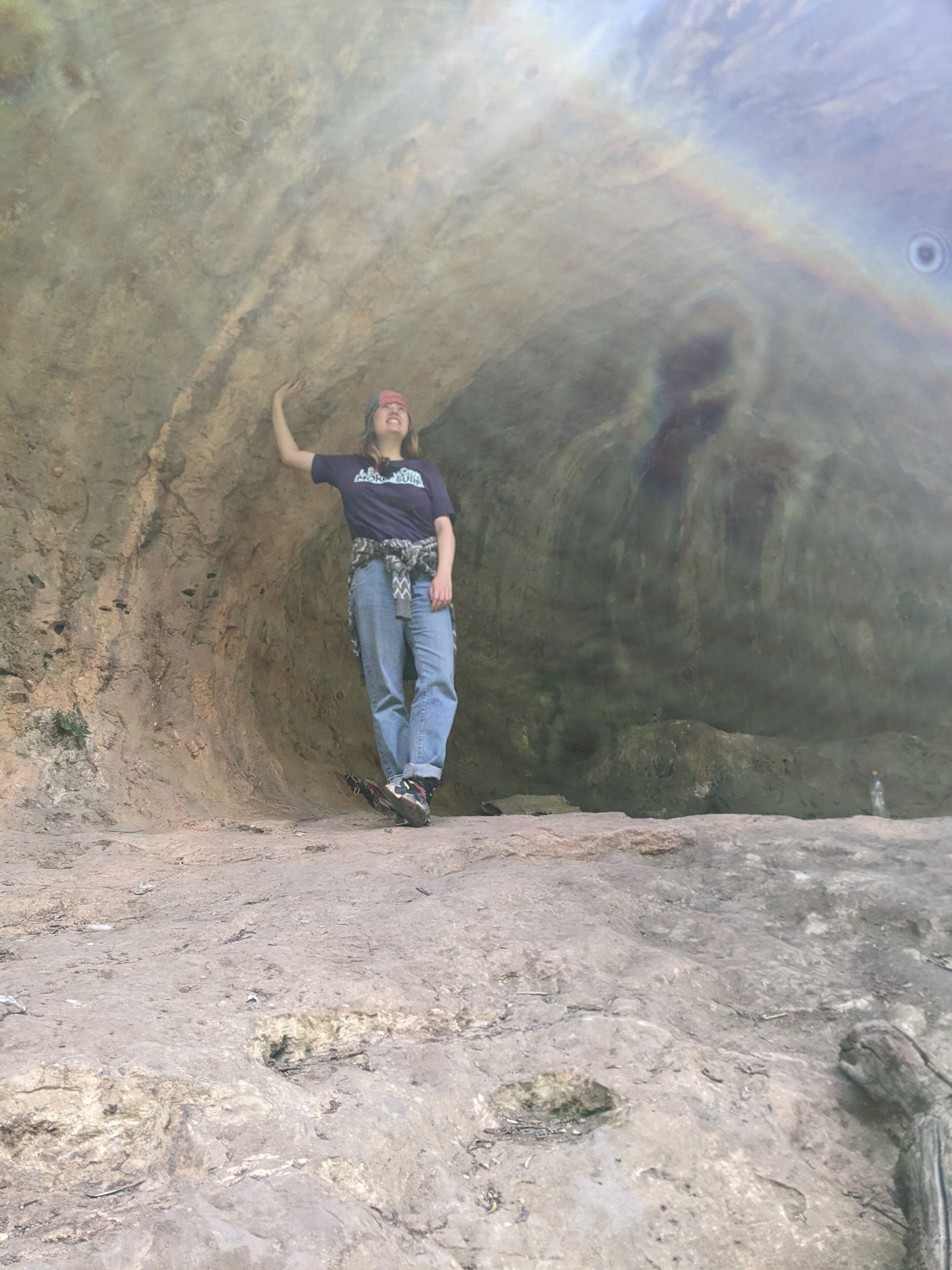 Una persona de pie en una cueva con un interior rocoso y accidentado.