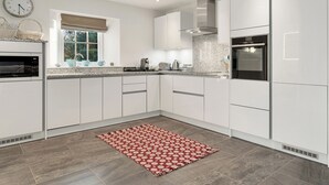 Une cuisine moderne avec des meubles blancs, un four encastré et un four à micro-ondes.