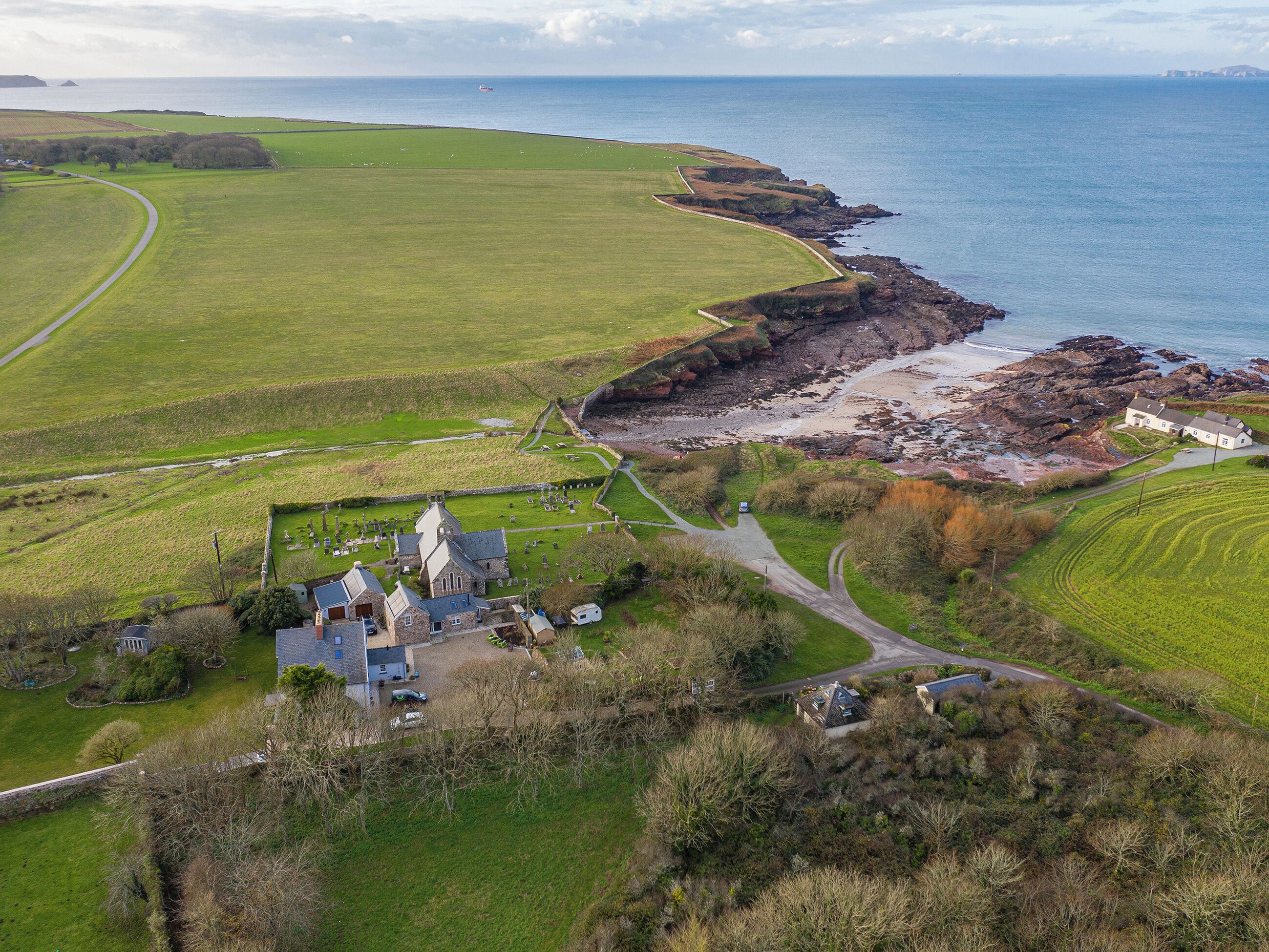 A coastal property with a stone church, a cemetery, and a rocky shoreline.