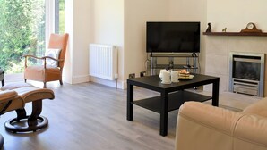 Una sala de estar con sofá, sillón, mesa de centro, chimenea y televisor.