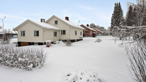 Una zona residencial cubierta de nieve con dos casas, una de tejado rojo y otra de tejado blanco.