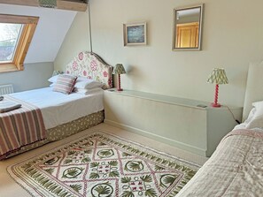 Un dormitorio con cama, mesita de noche, lámpara, ventana y espejo adosado a la pared.