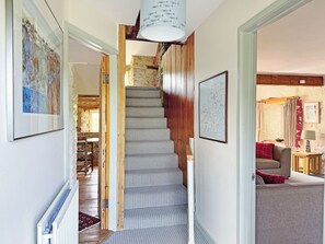 Una escalera de madera con peldaños y un suelo de alfombra estampada, que lleva a una habitación con una cama y una lámpara.