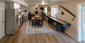 A kitchen with a dining area, a pool table, and a refrigerator.