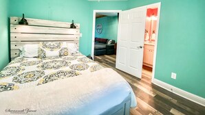 Une chambre à coucher avec un lit, un ventilateur de plafond et une porte donnant sur une salle de bain.
