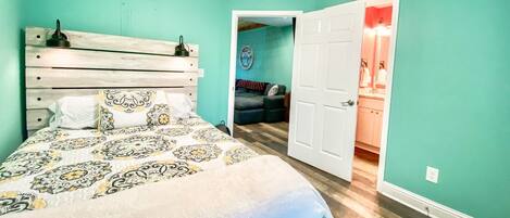 Une chambre à coucher avec un lit, un ventilateur de plafond et une porte donnant sur une salle de bain.