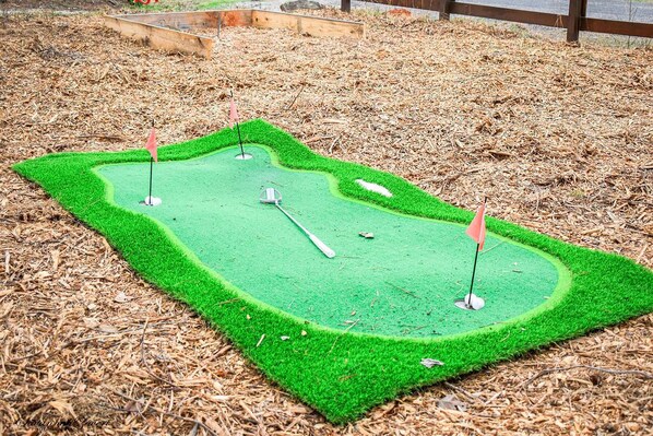 A miniature golf course with three holes, surrounded by mulch. - Romantic Treehouse Paradise (Clarks Hill)