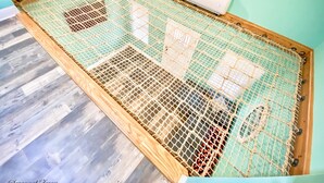 Une pièce avec un plancher en bois, un cadre de lit en métal ajouré et un appareil de climatisation blanc fixé au mur.