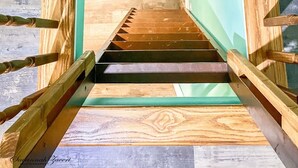 Un escalier avec des rampes en bois et un plancher en bois menant à une pièce dont un mur est peint en vert et qui possède une fenêtre.