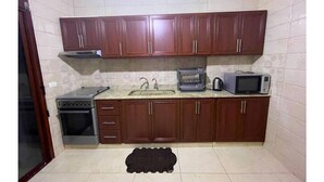 Une cuisine compacte avec des meubles en bois, un four encastré, un four à micro-ondes et un grille-pain.