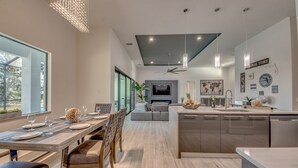 A modern kitchen with a dining area, large windows, and a ceiling fan. - Heated pool & spa | New | Canal | Bikes | BBQ (Cape Coral)