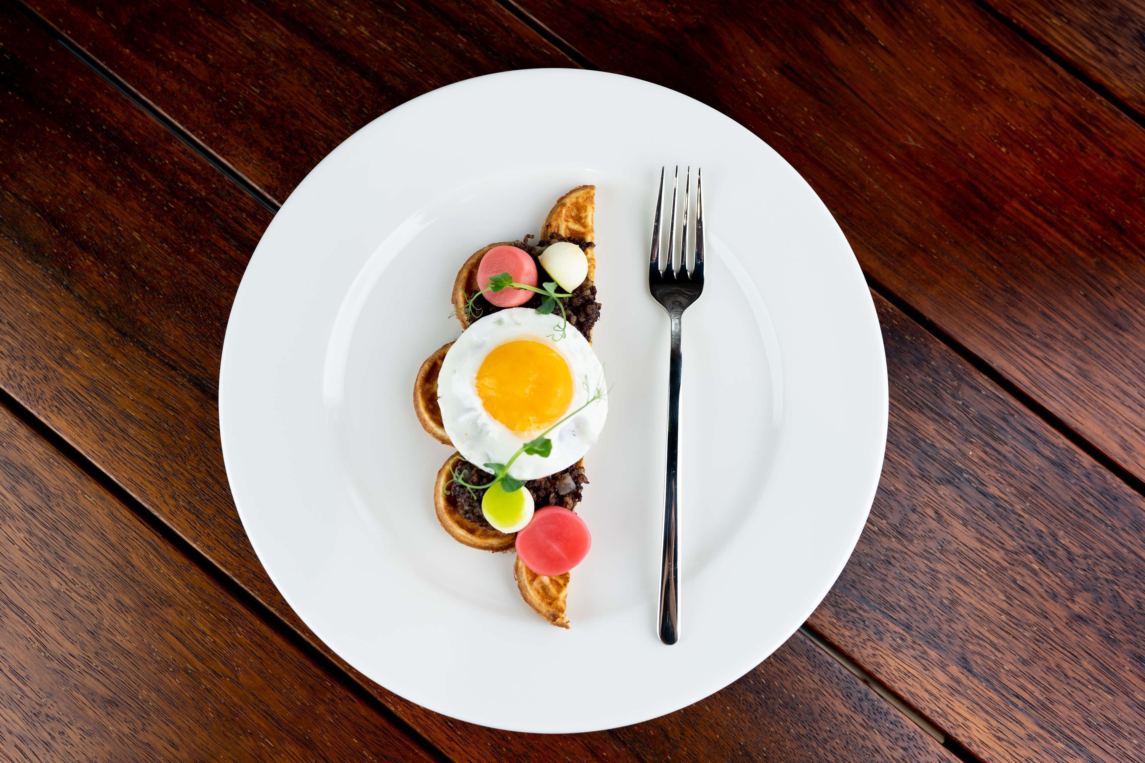 A white plate with a breakfast dish on a wooden table.