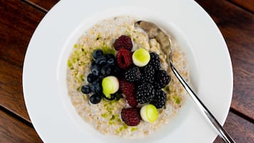 Un tazón de avena con bayas variadas y una cuchara.