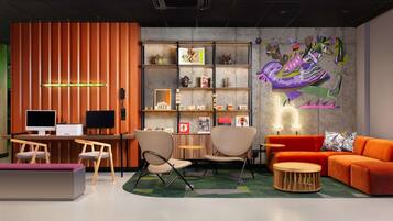 A modern lounge area with a wooden reception desk, two seating areas with chairs, a sofa, and a round wooden coffee table.