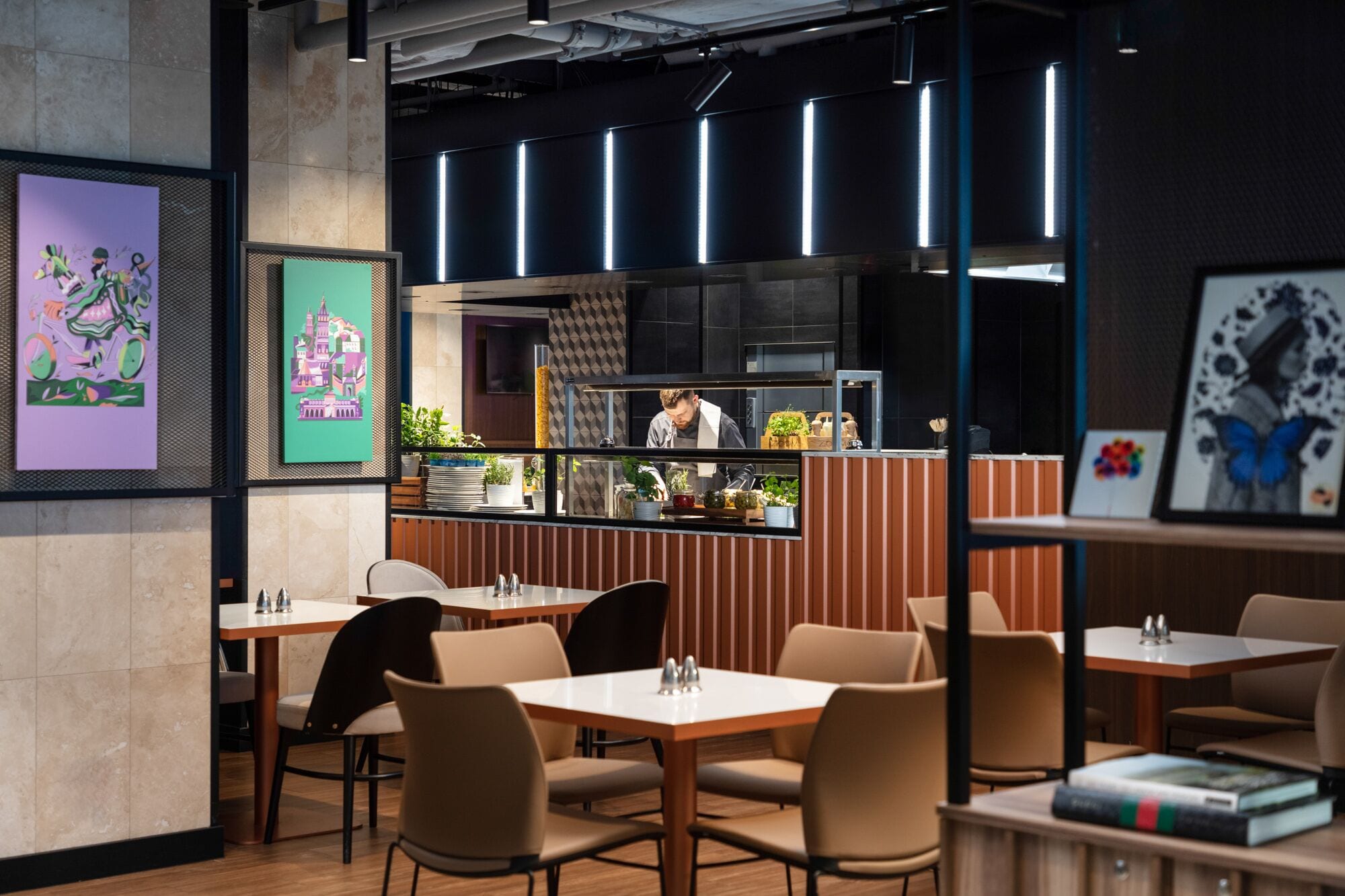 Un intérieur de restaurant moderne, avec un bar, des tables et des œuvres d’art accrochées aux murs.