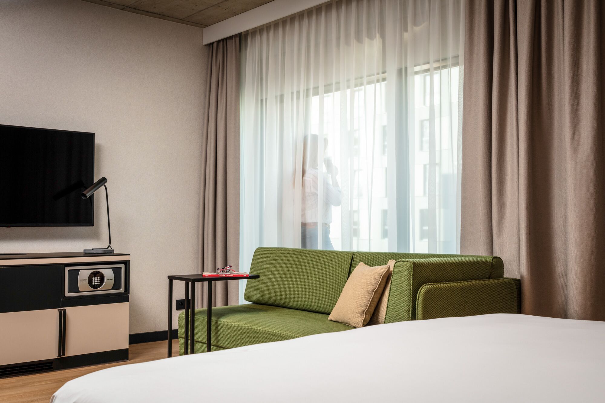 Una habitació d'hotel amb un llit, una televisió, una taula petita i un sofà.