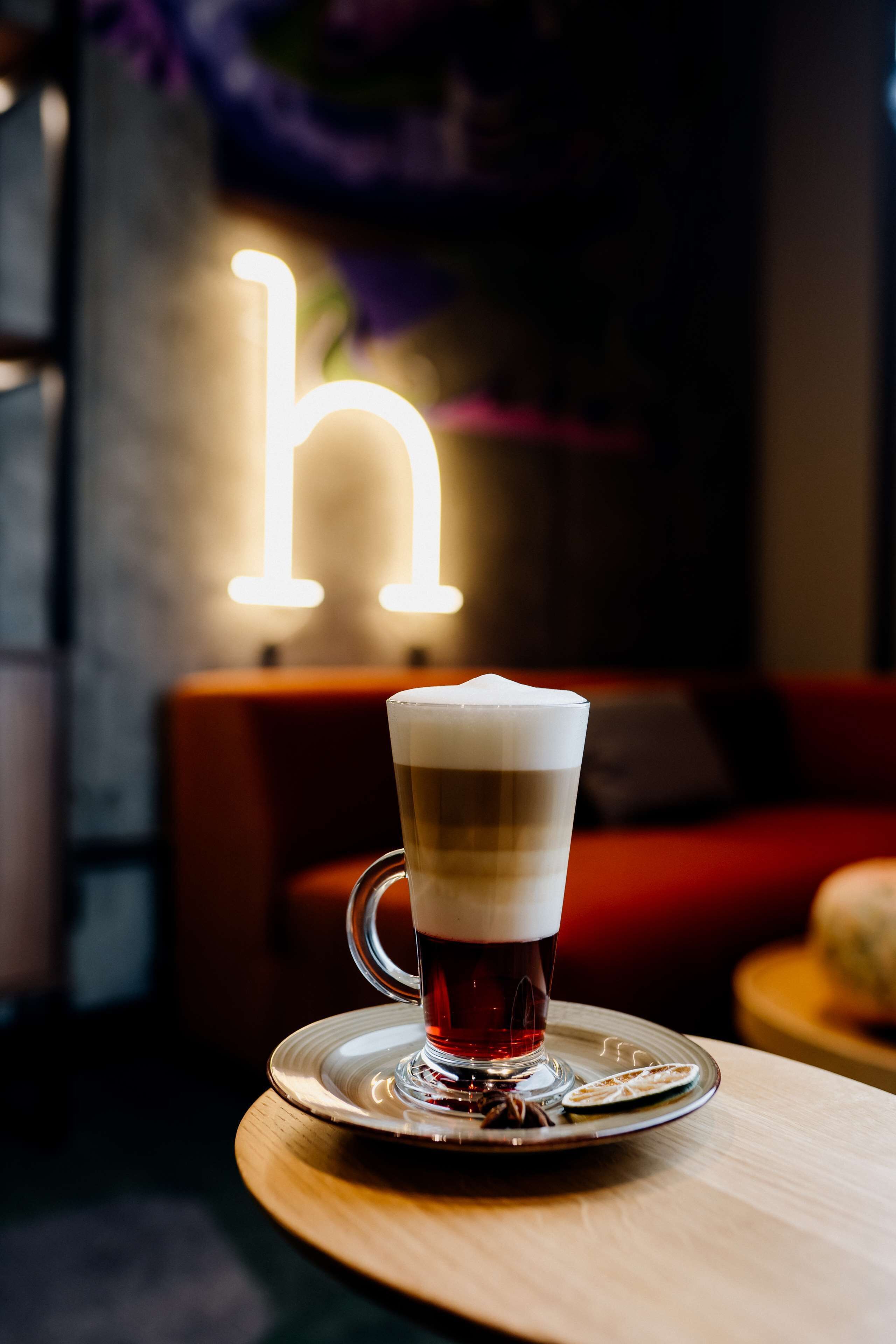Ein Bierglas auf einem Untersetzer, im Hintergrund ein leuchtendes 'h'-Schild.