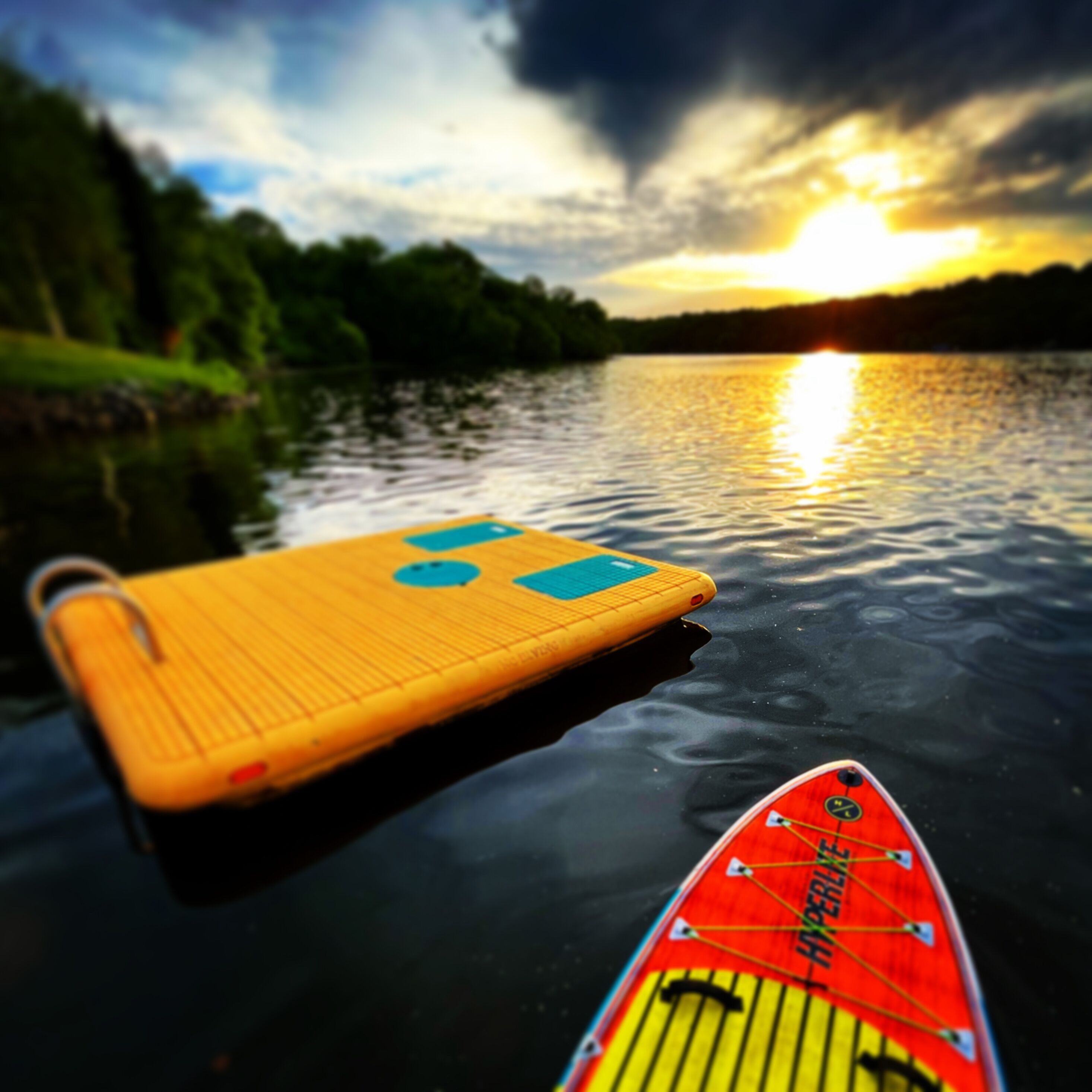 A paddleboard on calm water with a sunset in the background.