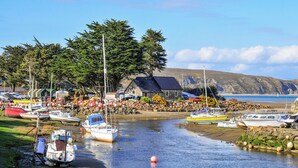 Ein Hafen mit Booten, ein Steinhaus und eine Bergkulisse.