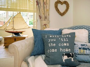 A cozy room with a bed, a heart-shaped decoration, a sailboat model, and a pillow with a cow illustration.