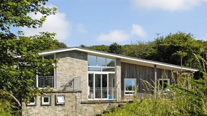 A modern house with a stone facade, large windows, and a balcony.
