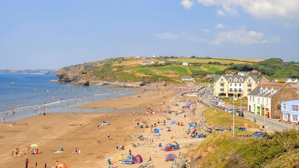 A beach with people, tents, and buildings along the shore.