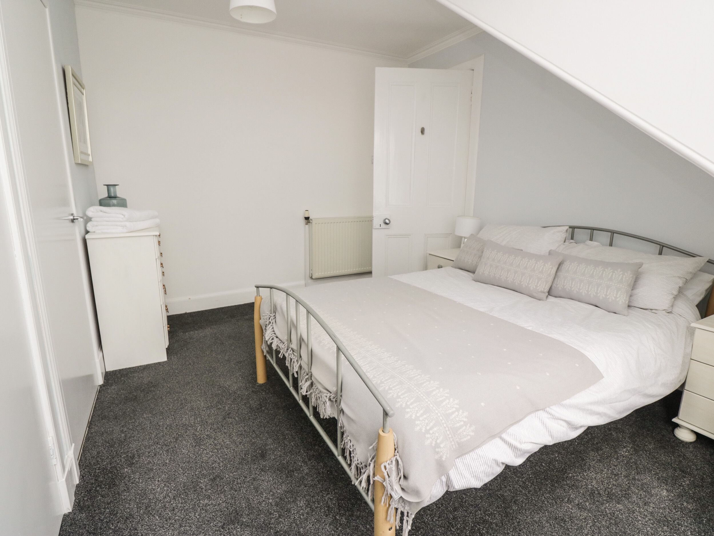 A bedroom with a bed, bedside table, and a wardrobe.