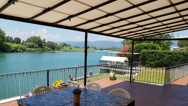 Un portico coperto con tavolo e sedie, con vista su un lago e montagne sullo sfondo.