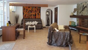Un soggiorno con divano, tavolino, scrivania con portatile, tappeto decorato e camino.
