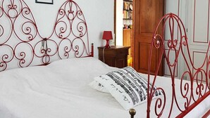 Una camera da letto con una struttura letto in metallo, un comodino, una lampada e un armadio.