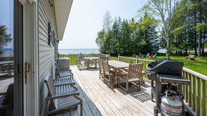 Eine Holzterrasse mit Gartenmöbeln, einem Grill und einem Propangasbehälter.